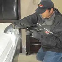 Bed bug inspection technician checking a mattress and bed frame for signs of infestation in Yonkers, NY