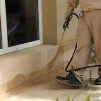 General pest control technician spraying exterior perimeter around a home in Yonkers, NY