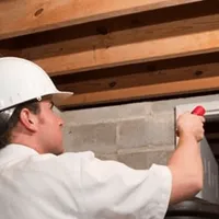 Termite inspection technician checking a basement wall and framing for termite activity in Yonkers, NY