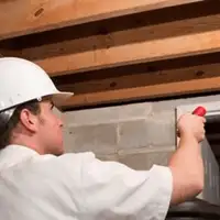 Termite inspection technician checking a basement wall and framing for termite activity in Yonkers, NY